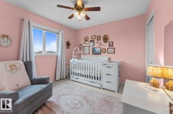 Bright room featuring a window with white trim, a ceiling fan with light fixture, carpet flooring, a white paneled door, and a built-in closet - 