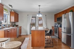 Kitchen featuring hardwood-finish flooring, wood cabinetry, a center island with seating, stainless steel appliances, and a glass-paneled door - 