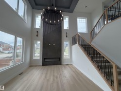 Living Room featuring a contemporary linear fireplace with stone-look surround, a decorative chandelier, and light wood-finish flooring - 