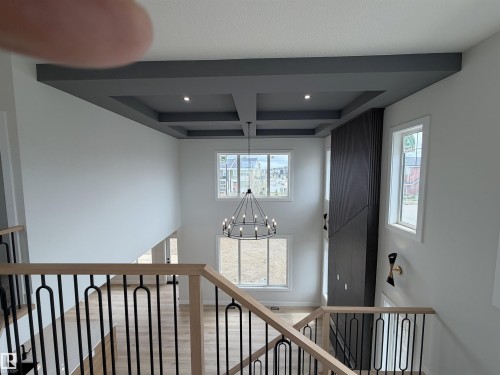 Two-story foyer featuring a coffered ceiling with recessed lighting, a modern chandelier, and light wood-finish flooring - 202 Edgewater Circle, Leduc, AB - Indoor Photo Showing Other Room