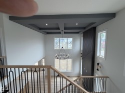 Two-story foyer featuring a coffered ceiling with recessed lighting, a modern chandelier, and light wood-finish flooring - 