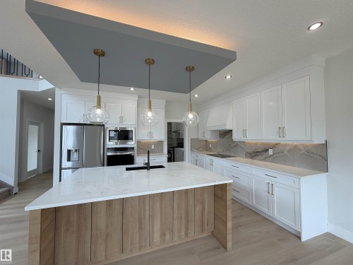 Gourmet kitchen featuring a large central island with wood-finish paneling and a quartz countertop - 202 Edgewater Circle, Leduc, AB - Indoor Photo Showing Kitchen With Upgraded Kitchen