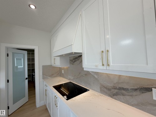 Contemporary kitchen with white shaker cabinetry, gold-tone hardware, and a built-in cooktop - 202 Edgewater Circle, Leduc, AB - Indoor Photo Showing Kitchen