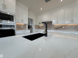 Kitchen featuring a large island with a black undermount sink and matte black faucet - 