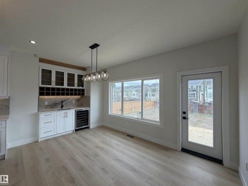 Wet bar featuring white cabinetry, glass-front upper cabinets, a built-in wine rack, and a beverage cooler - 202 Edgewater Circle, Leduc, AB - Indoor