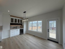 Wet bar featuring white cabinetry, glass-front upper cabinets, a built-in wine rack, and a beverage cooler - 