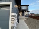 Exterior featuring multi-toned stone accents, dark horizontal siding, and white window trim - 202 Edgewater Circle, Leduc, AB  - Outdoor 