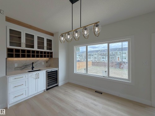 Built-in wet bar featuring white cabinetry, glass-front upper cabinets, and integrated wine storage - 202 Edgewater Circle, Leduc, AB - Indoor Photo Showing Other Room