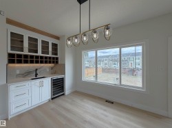 Built-in wet bar featuring white cabinetry, glass-front upper cabinets, and integrated wine storage - 