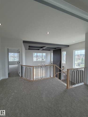 Upper-level landing featuring neutral carpeting, contemporary baluster railing, recessed lighting, and a coffered ceiling detail with an integrated chandelier - 202 Edgewater Circle, Leduc, AB - Indoor Photo Showing Other Room