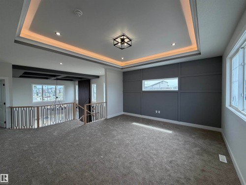 Spacious open area featuring a tray ceiling with recessed lighting and a central light fixture - 202 Edgewater Circle, Leduc, AB - Indoor Photo Showing Other Room