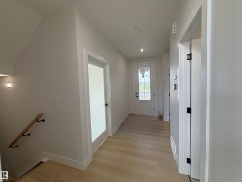 Entryway featuring light wood-finish flooring, white trim, and a glass-paneled entry door - 202 Edgewater Circle, Leduc, AB - Indoor Photo Showing Other Room