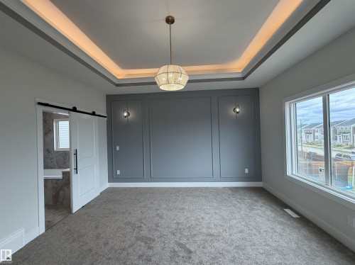 Tray ceiling with perimeter lighting and a central chandelier - 202 Edgewater Circle, Leduc, AB - Indoor Photo Showing Other Room