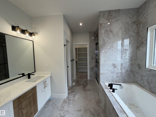 Contemporary bathroom featuring a spacious vanity with white cabinetry, wood-finish drawers, and a white countertop - 202 Edgewater Circle, Leduc, AB - Indoor Photo Showing Bathroom