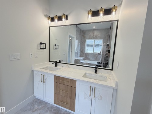 Dual vanity with white cabinetry, wood-finish drawers, and gold-tone hardware - 202 Edgewater Circle, Leduc, AB - Indoor Photo Showing Bathroom