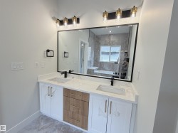 Dual vanity with white cabinetry, wood-finish drawers, and gold-tone hardware - 