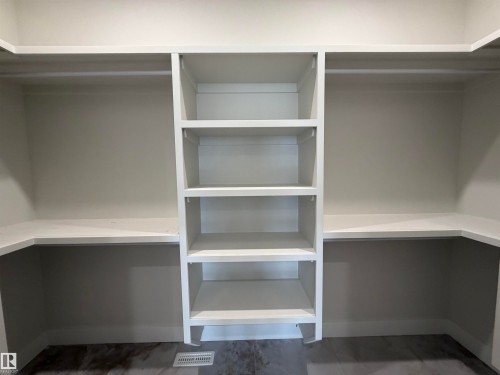 Walk-in closet featuring built-in shelving, hanging rods, and perimeter countertops - 202 Edgewater Circle, Leduc, AB - Indoor With Storage