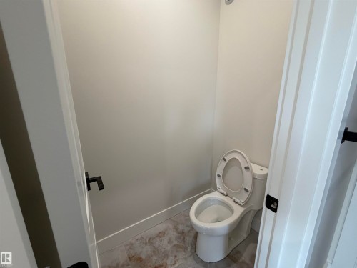 Contemporary water closet featuring a two-piece toilet, light-toned wall paint, and patterned floor tiles - 202 Edgewater Circle, Leduc, AB - Indoor Photo Showing Bathroom