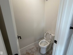 Contemporary water closet featuring a two-piece toilet, light-toned wall paint, and patterned floor tiles - 