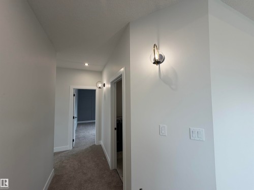 Hallway with recessed lighting, wall sconces, white baseboards, and neutral-toned carpeting - 202 Edgewater Circle, Leduc, AB - Indoor Photo Showing Other Room
