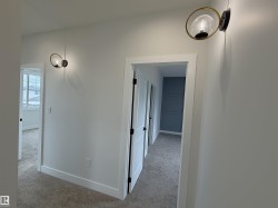 Hallway featuring two contemporary wall sconces with clear glass shades and brass-finish accents - 