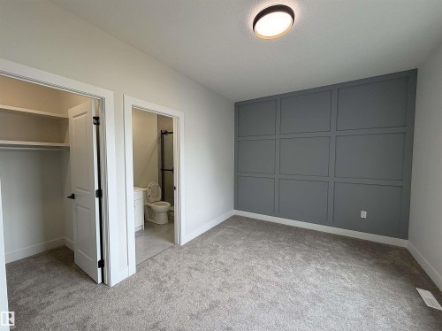 Carpeted room featuring a decorative accent wall with panel molding, a flush-mount ceiling light, and white baseboards - 202 Edgewater Circle, Leduc, AB - Indoor Photo Showing Other Room
