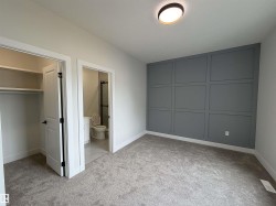 Carpeted room featuring a decorative accent wall with panel molding, a flush-mount ceiling light, and white baseboards - 