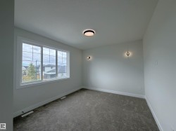 Spacious room featuring a large multi-pane window, neutral-toned carpeting, and light gray wall paint - 