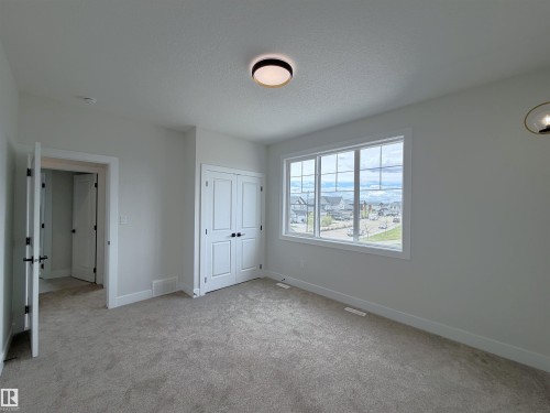 Interior room featuring light gray carpeting, white walls, and a large multi-pane window - 202 Edgewater Circle, Leduc, AB - Indoor Photo Showing Other Room