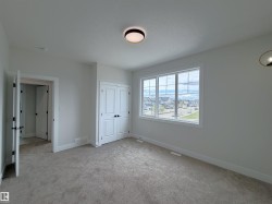 Interior room featuring light gray carpeting, white walls, and a large multi-pane window - 