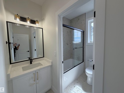 Contemporary bathroom vanity featuring a rectangular undermount sink, a white countertop, and a matte black faucet - 202 Edgewater Circle, Leduc, AB - Indoor Photo Showing Bathroom