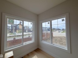 Bright interior space featuring two large windows with white trim, grid patterns, and light wood-finish flooring - 