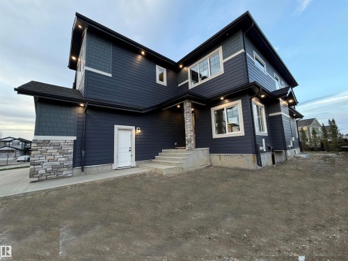 Contemporary two-story exterior featuring dark blue siding with gray shingle accents and white trim - 202 Edgewater Circle, Leduc, AB - Outdoor
