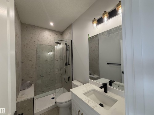 Modern bathroom featuring a walk-in shower with a glass enclosure, a built-in shower bench, and dark-finish fixtures - 202 Edgewater Circle, Leduc, AB - Indoor Photo Showing Bathroom