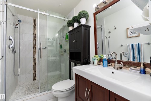 Bathroom featuring a glass-enclosed shower with pebble-finish flooring and a decorative tile accent strip - 17 Camelot Avenue, Leduc, AB - Indoor Photo Showing Bathroom