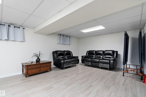 Spacious room featuring light-toned rectangular floor tiles, white walls, and a drop ceiling with recessed lighting - 17 Camelot Avenue, Leduc, AB - Indoor Photo Showing Basement