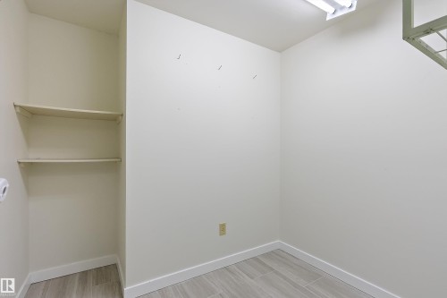 Utility space featuring neutral-toned walls, two built-in shelves, wood-finish flooring, and a flush-mount overhead light fixture - 17 Camelot Avenue, Leduc, AB - Indoor