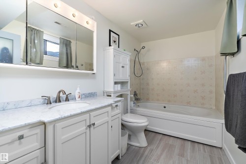 Bathroom featuring a white vanity with a light-colored countertop, an undermount sink, and brushed nickel fixtures - 17 Camelot Avenue, Leduc, AB - Indoor Photo Showing Bathroom
