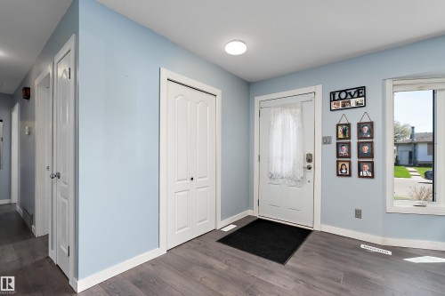Entryway featuring wood-finish flooring, light blue wall paint, white baseboards, and a white front door with decorative glass - 17 Camelot Avenue, Leduc, AB - Indoor Photo Showing Other Room