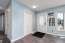Entryway featuring wood-finish flooring, light blue wall paint, white baseboards, and a white front door with decorative glass - 17 Camelot Avenue, Leduc, AB  - Indoor Photo Showing Other Room 