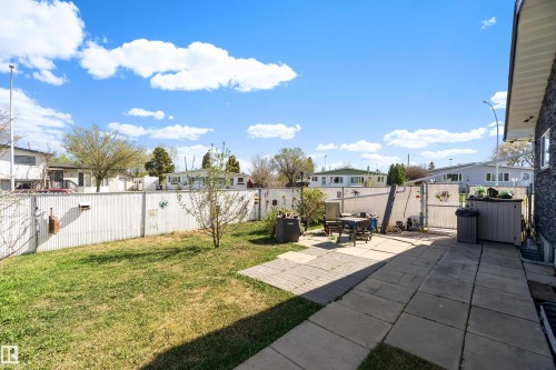 Expansive backyard featuring a manicured lawn, a paved patio area, and white perimeter fencing - 17 Camelot Avenue, Leduc, AB - Outdoor