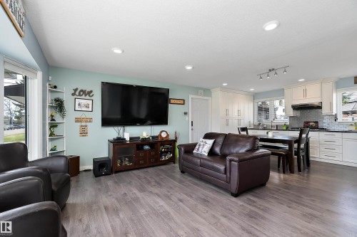 Open-concept living space featuring wood-finish flooring, recessed lighting, and a white kitchen with shaker cabinetry - 17 Camelot Avenue, Leduc, AB - Indoor Photo Showing Living Room
