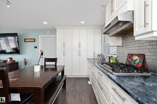 Kitchen featuring white cabinetry, dark stone countertops, stainless steel range hood, subway tile backsplash, and recessed lighting - 17 Camelot Avenue, Leduc, AB - Indoor