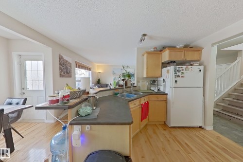 The kitchen features light-toned wooden cabinetry and hardwood floors - 3120 25 Avenue Nw, Edmonton, AB - Indoor Photo Showing Kitchen With Double Sink