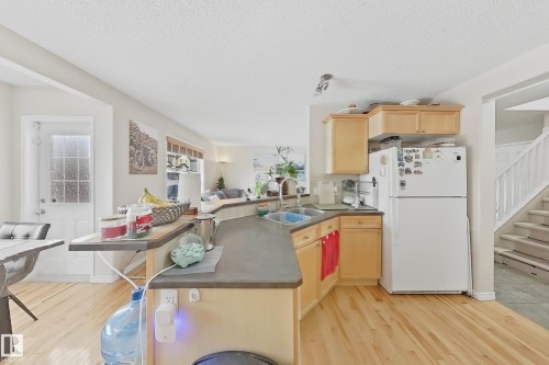 The kitchen features light wood cabinetry, a double basin sink, and a refrigerator - 3120 25 Avenue Nw, Edmonton, AB - Indoor Photo Showing Kitchen With Double Sink