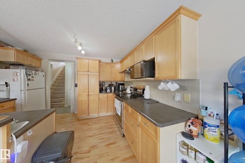 The kitchen features light wood cabinetry, dark countertops, and light wood flooring - 3120 25 Avenue Nw, Edmonton, AB - Indoor Photo Showing Kitchen
