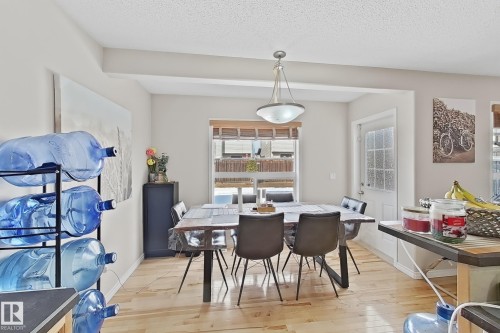 Dining area with light wood flooring, a window providing natural light, and a white door with frosted glass panels - 3120 25 Avenue Nw, Edmonton, AB - Indoor Photo Showing Dining Room