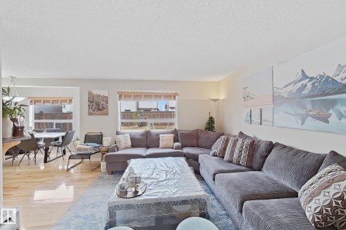 The open living area features light-toned hardwood flooring in the dining space and a large area rug in the seating area - 3120 25 Avenue Nw, Edmonton, AB - Indoor Photo Showing Living Room