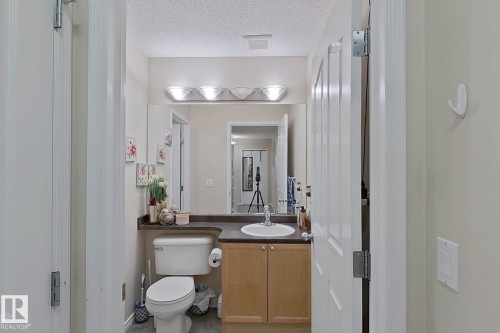 Bathroom with a vanity featuring a white sink, light wood cabinetry, and a mirror with overhead lighting - 3120 25 Avenue Nw, Edmonton, AB - Indoor Photo Showing Bathroom