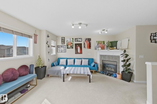 This living area features a fireplace with a white mantel and a large window providing natural light - 3120 25 Avenue Nw, Edmonton, AB - Indoor With Fireplace
